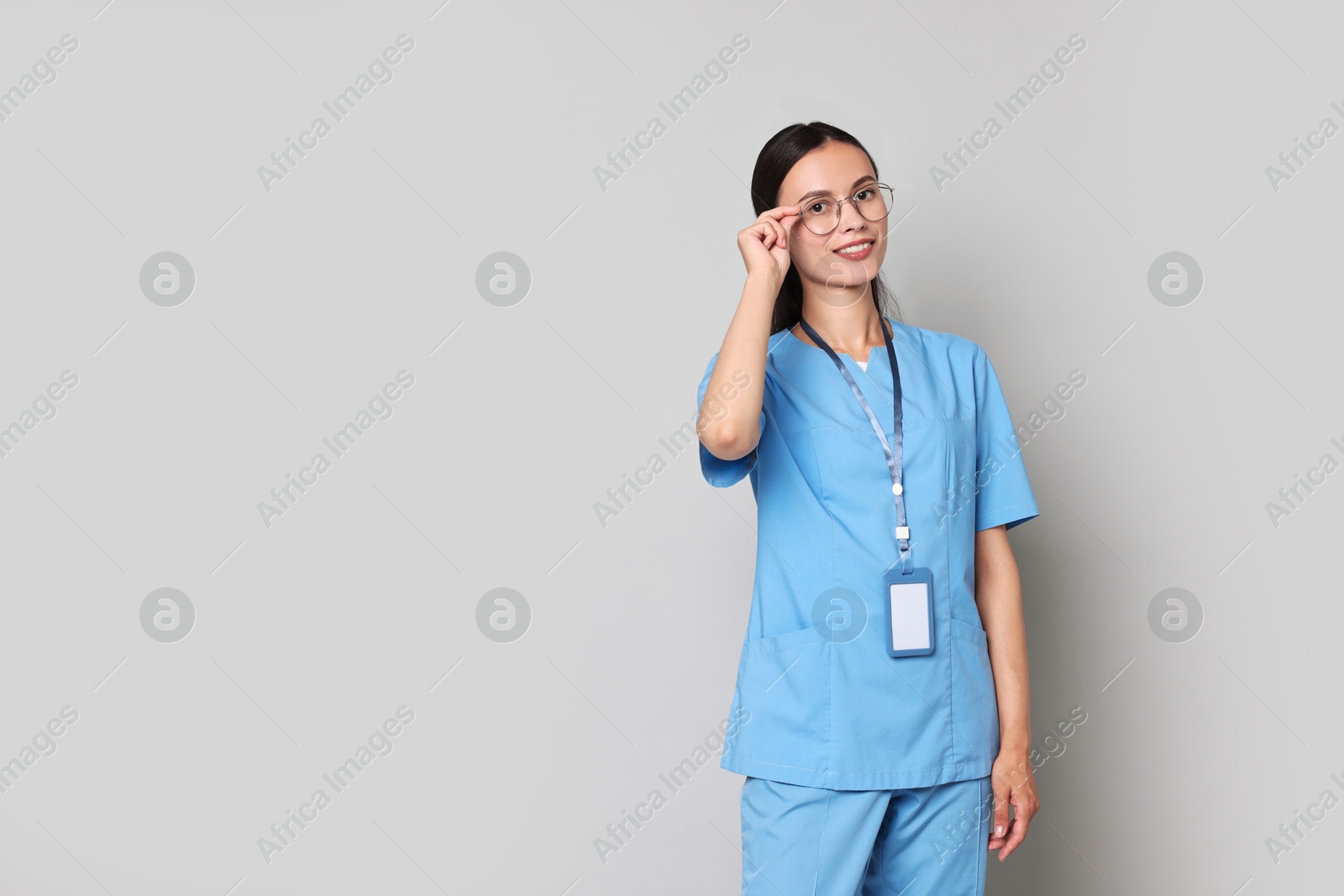 Photo of Smiling nurse in uniform on grey background. Space for text