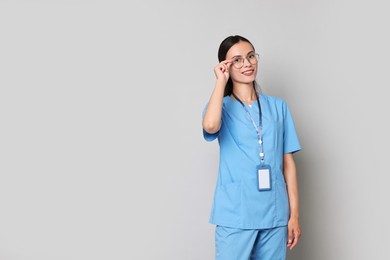 Photo of Smiling nurse in uniform on grey background. Space for text