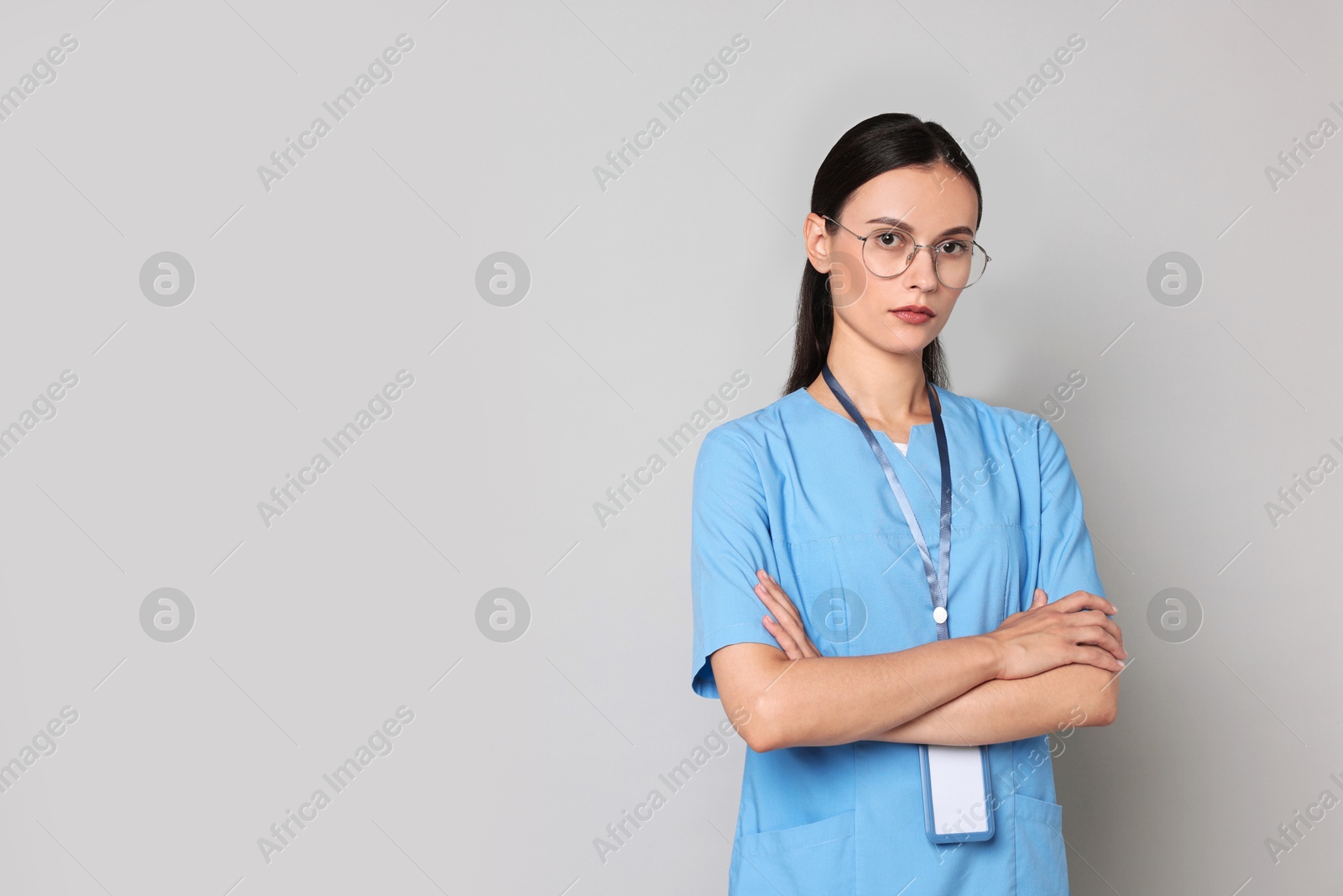 Photo of Beautiful nurse with crossed arms on grey background. Space for text