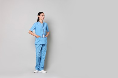 Photo of Smiling nurse in uniform on grey background. Space for text