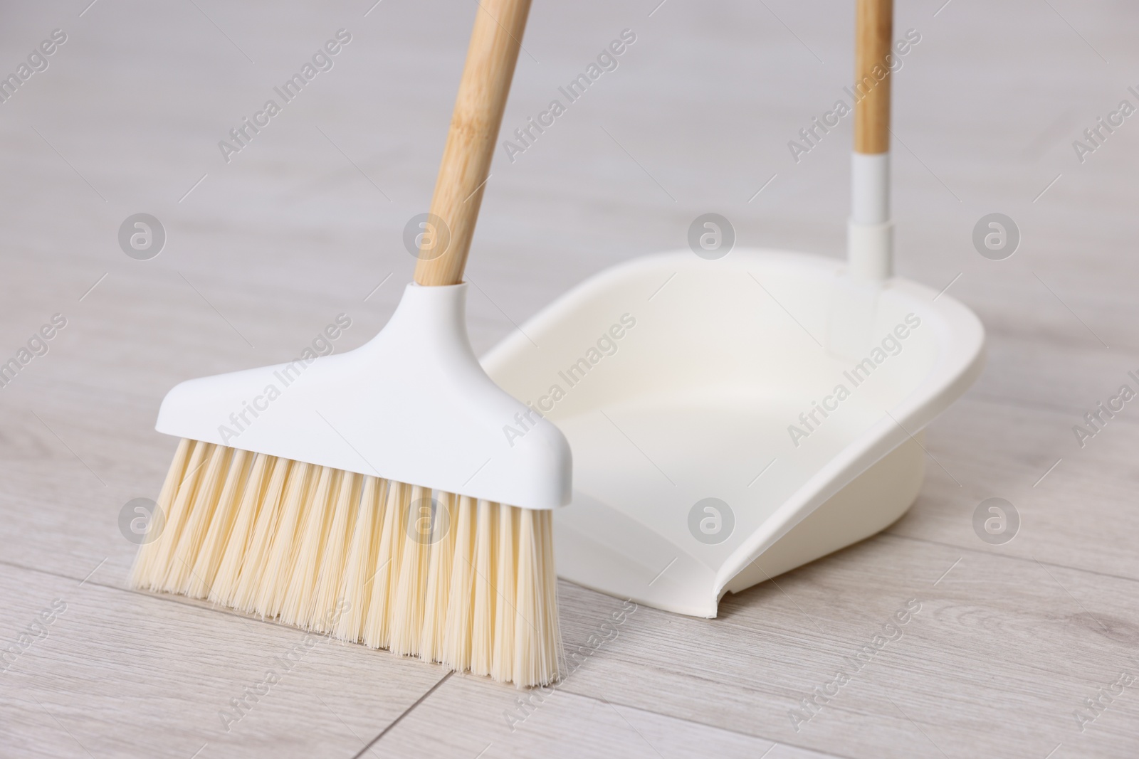 Photo of Cleaning broom and dustpan on wooden floor