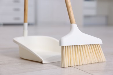 Cleaning broom and dustpan on wooden floor indoors