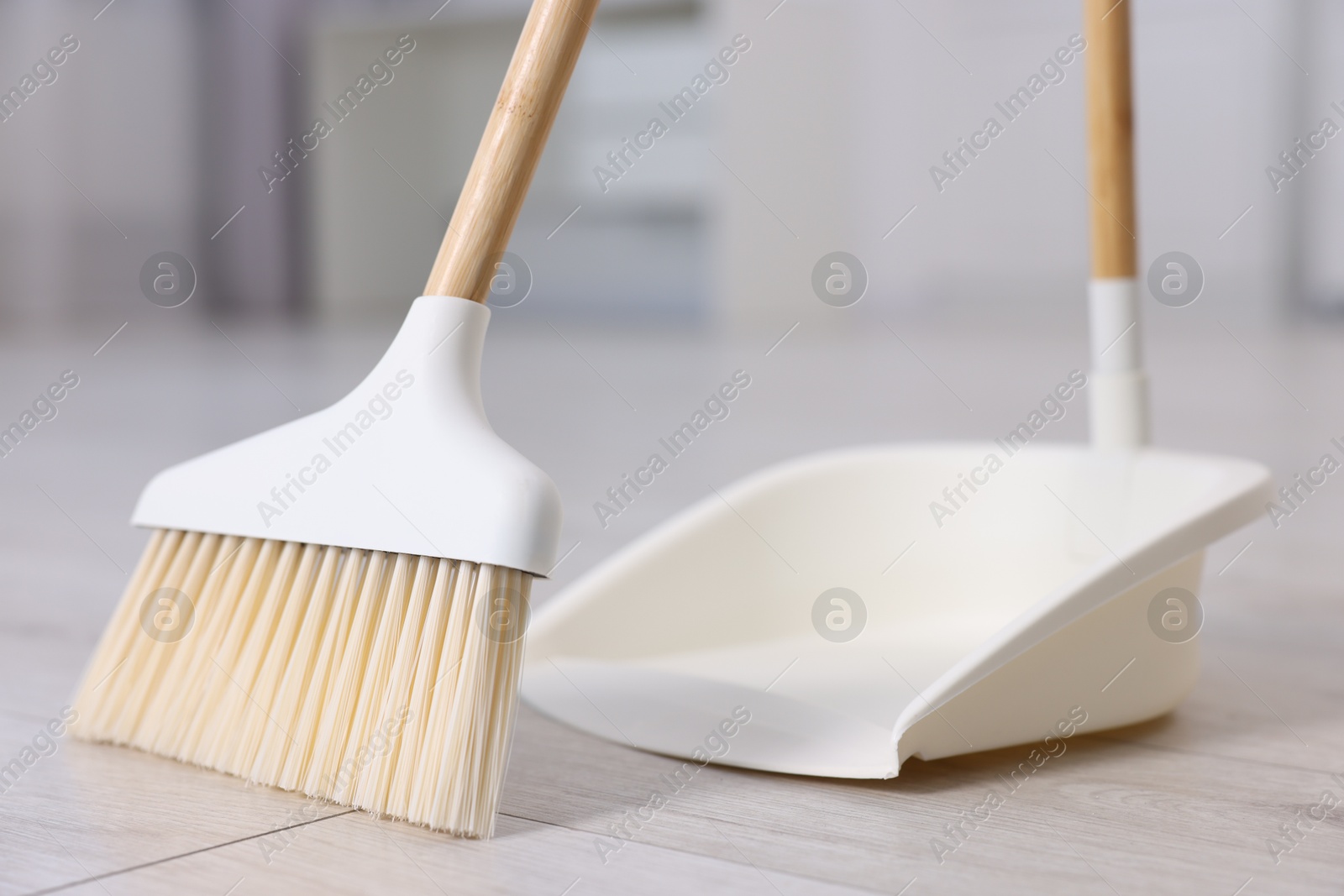 Photo of Cleaning broom and dustpan on wooden floor indoors