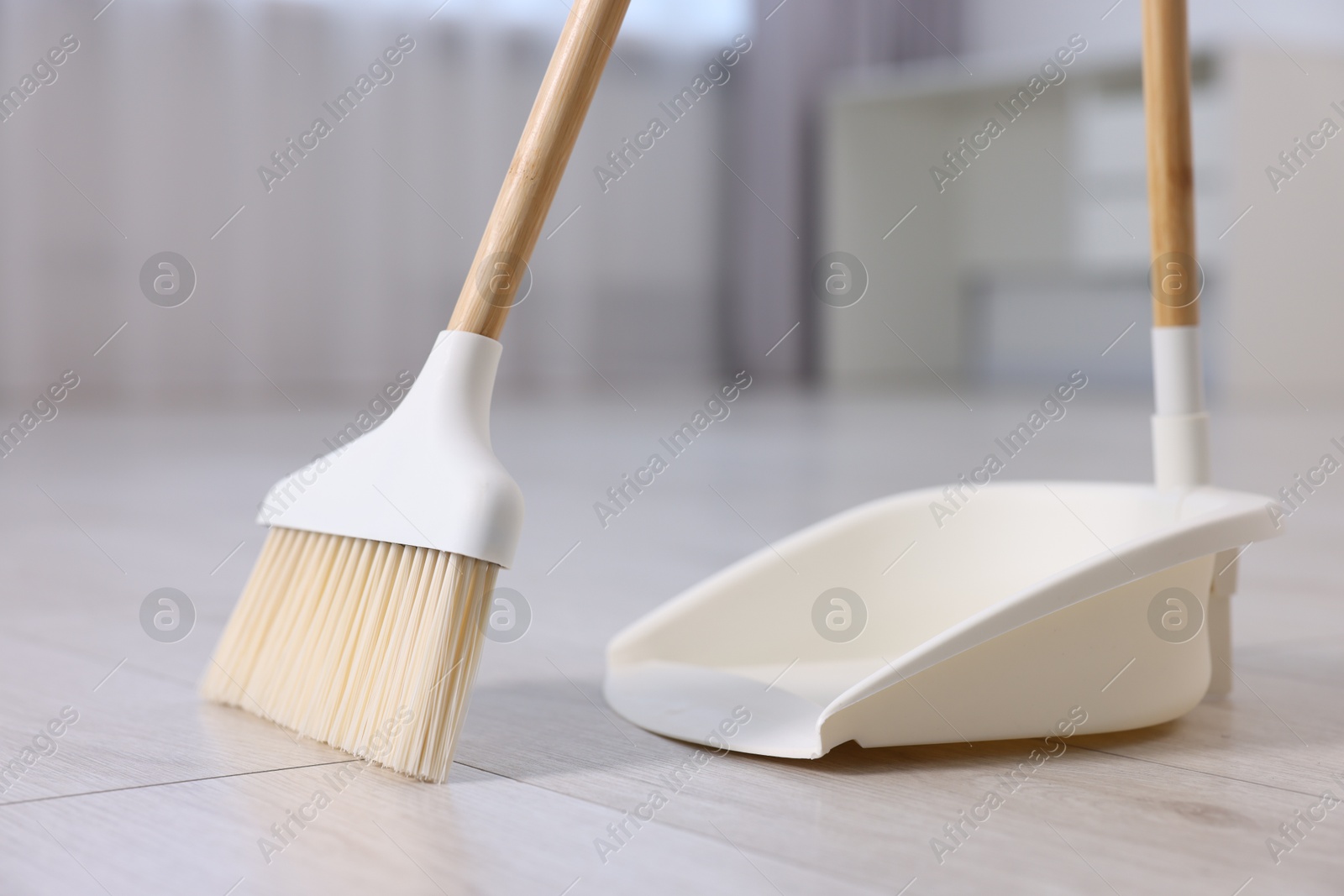 Photo of Cleaning broom and dustpan on wooden floor indoors