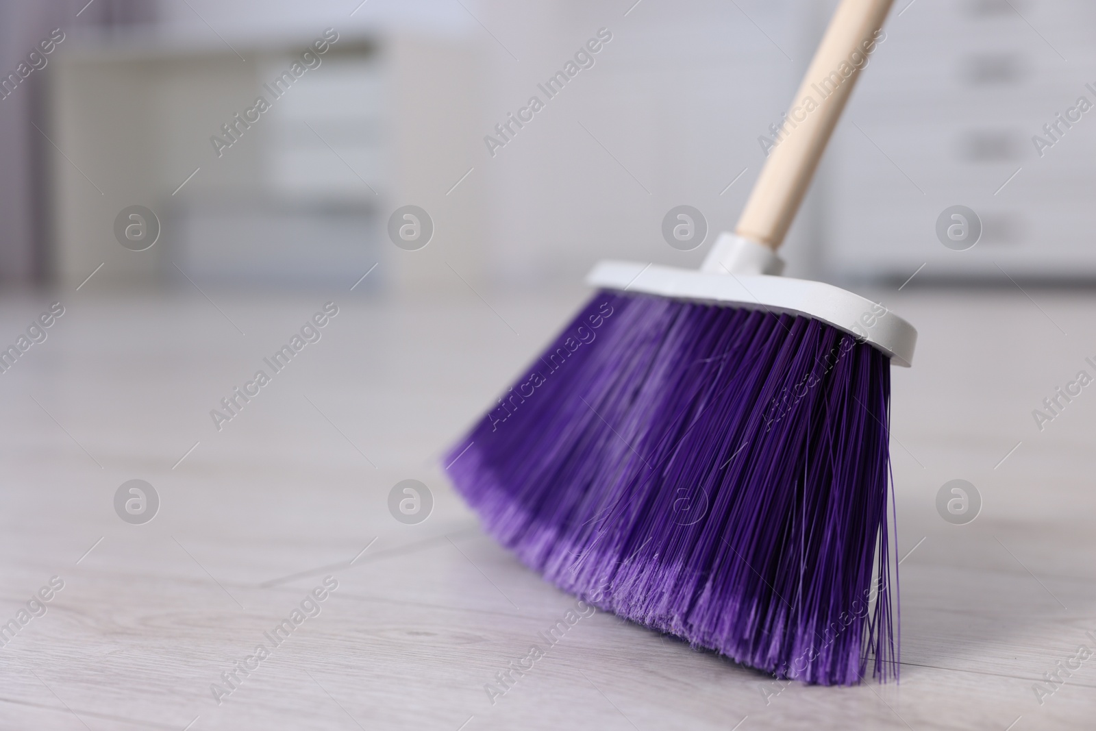 Photo of Cleaning broom on wooden floor indoors, closeup. Space for text