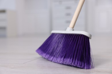 Photo of One cleaning broom on wooden floor indoors, closeup