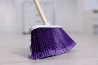 Photo of One cleaning broom on wooden floor indoors, closeup