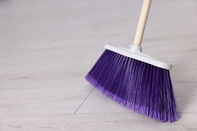 Cleaning broom on wooden floor, space for text