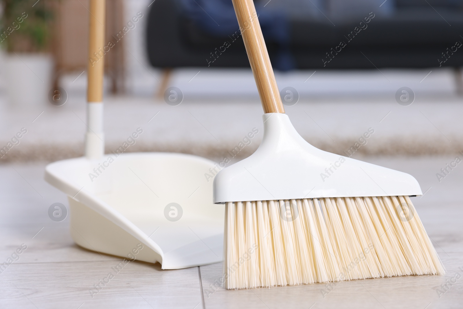 Photo of Cleaning broom and dustpan on wooden floor indoors