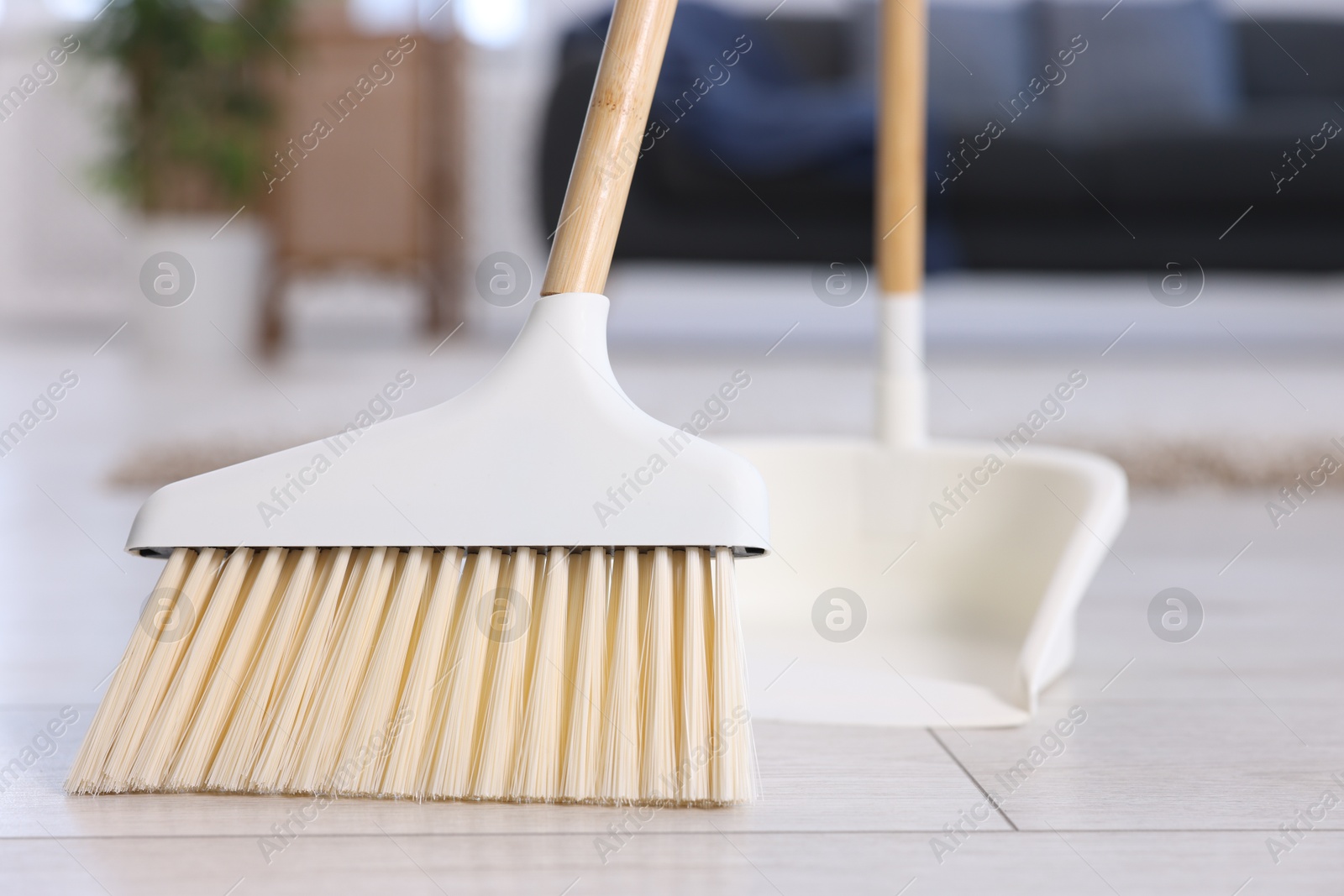 Photo of Cleaning broom and dustpan on wooden floor indoors