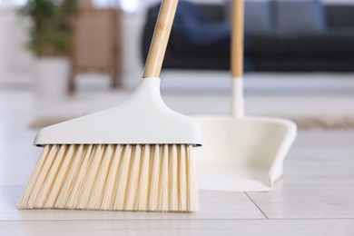 Cleaning broom and dustpan on wooden floor indoors