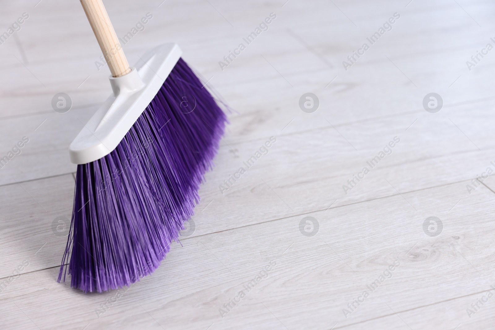 Photo of Cleaning broom on wooden floor, space for text