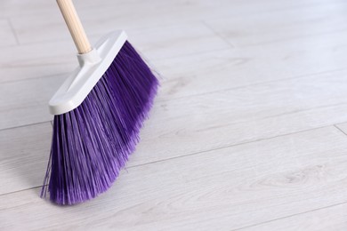 Cleaning broom on wooden floor, space for text