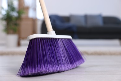 Photo of One cleaning broom on wooden floor indoors, closeup