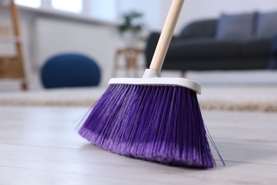 Photo of One cleaning broom on wooden floor indoors, closeup