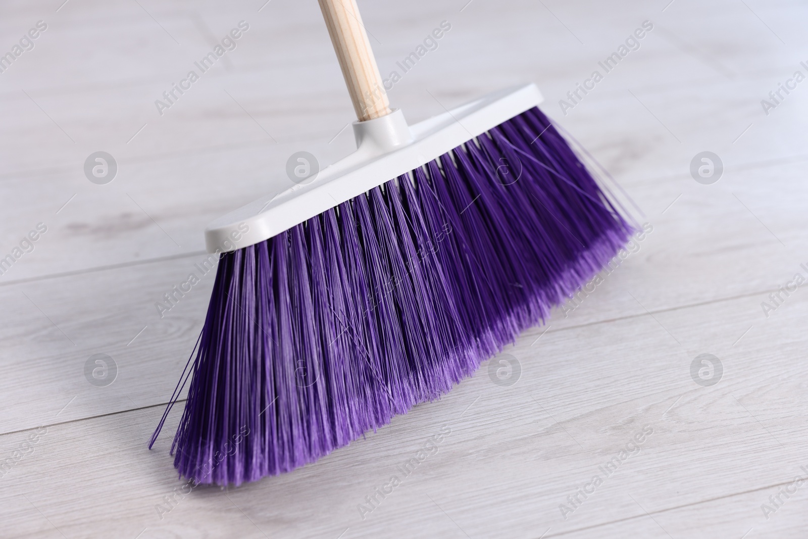 Photo of One bright cleaning broom on wooden floor, closeup