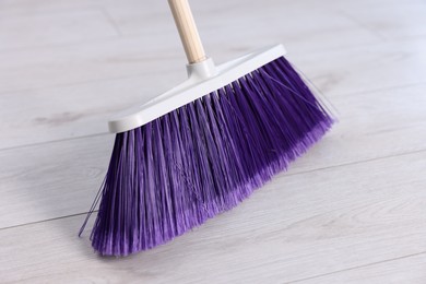 One bright cleaning broom on wooden floor, closeup