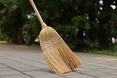 One corn straw broom on pavement outdoors