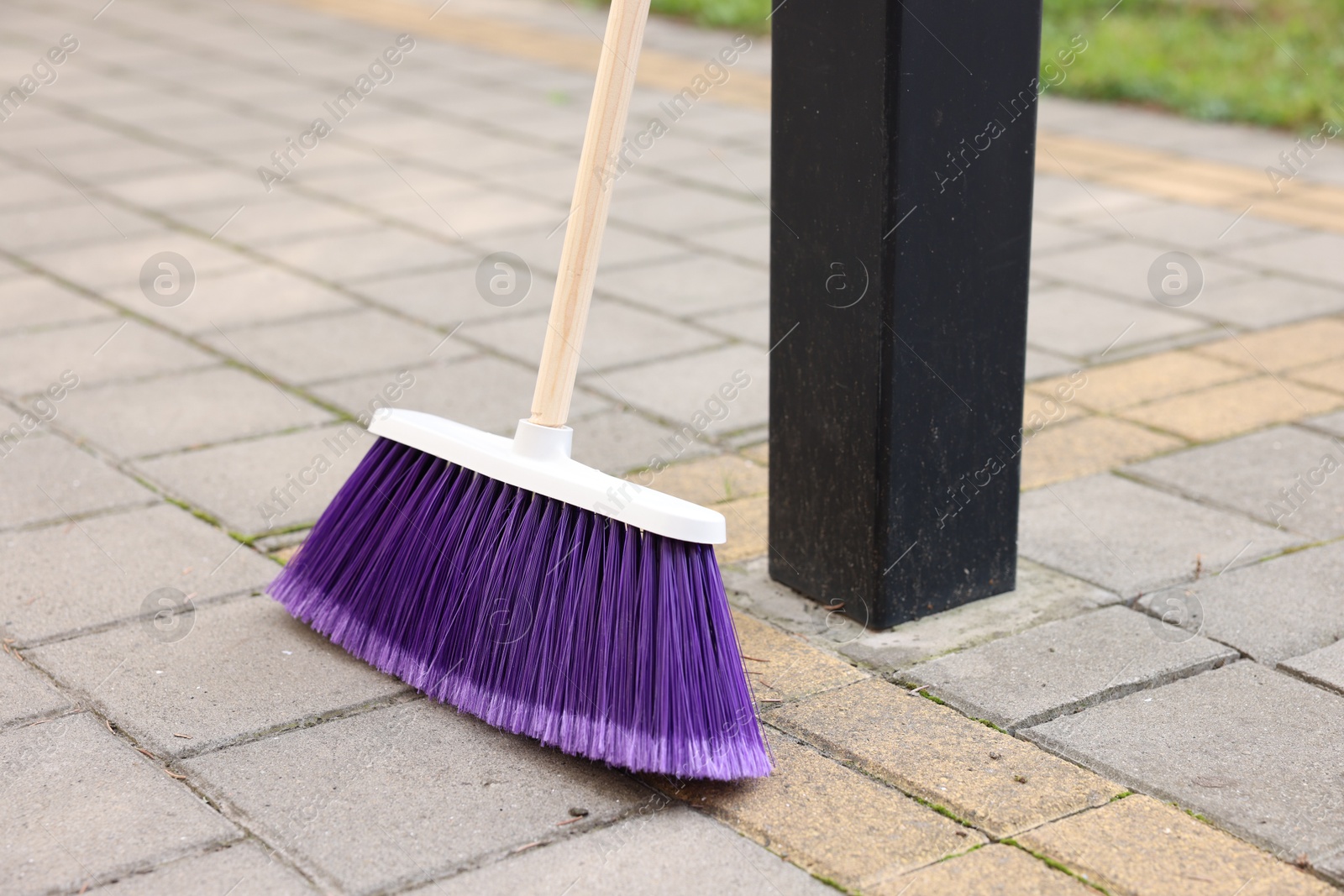 Photo of One bright cleaning broom on pavement outdoors