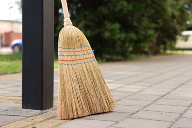 Photo of One corn straw broom on pavement outdoors, space for text