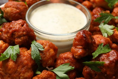 Photo of Baked cauliflower buffalo wings with parsley and sauce on plate, closeup