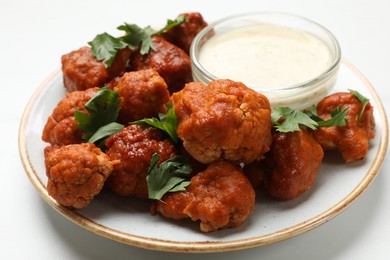 Photo of Baked cauliflower buffalo wings with parsley and sauce on white table, closeup