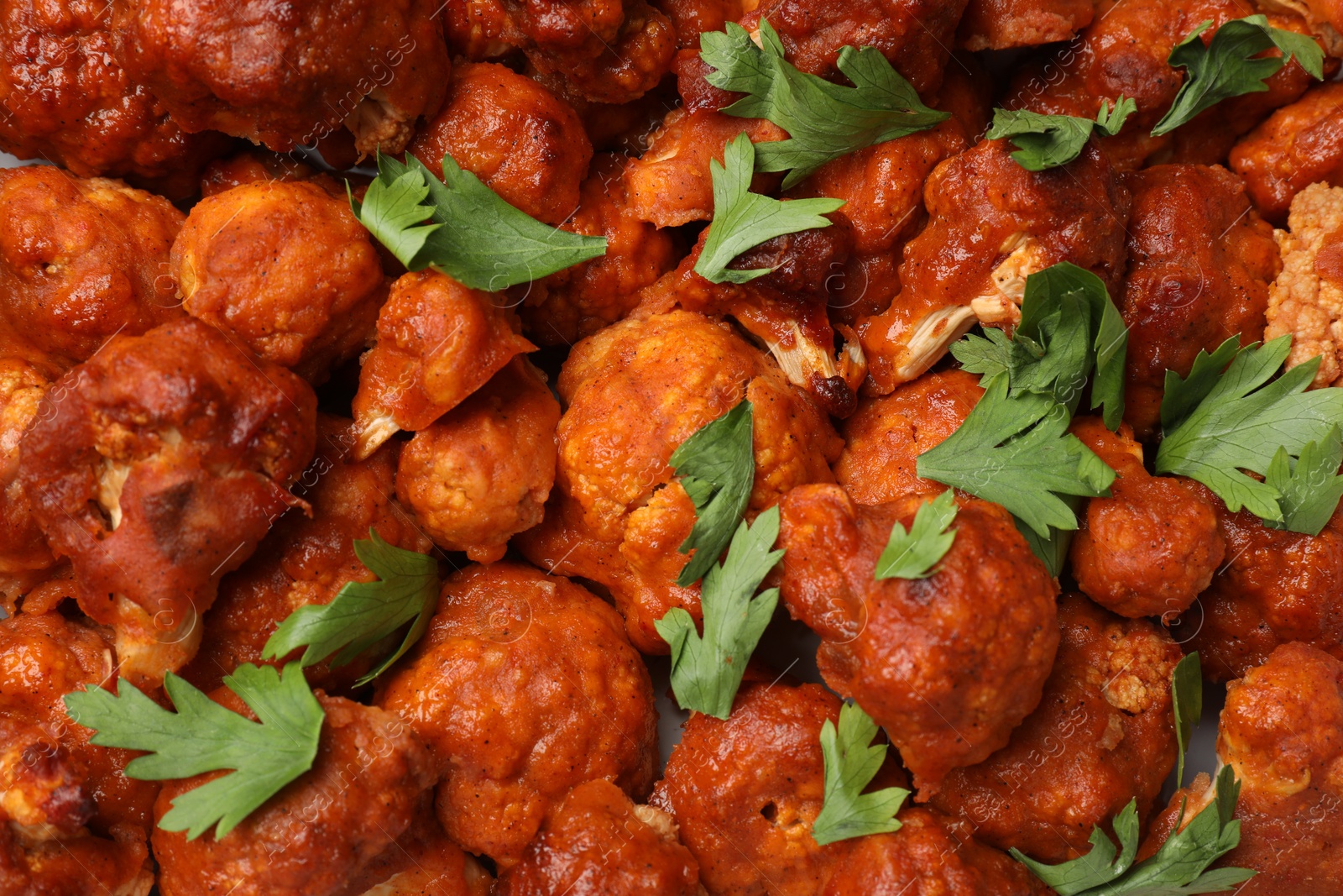 Photo of Baked cauliflower buffalo wings with parsley as background, top view