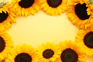 Photo of Frame made of sunflower heads on yellow background, flat lay. Space for text