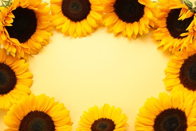 Photo of Frame made of sunflower heads on yellow background, flat lay. Space for text