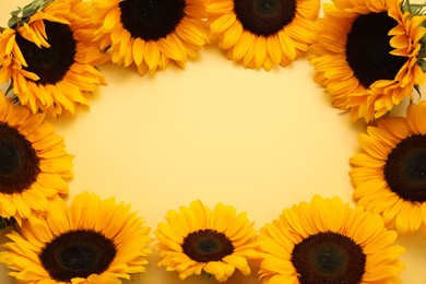 Photo of Frame made of sunflower heads on yellow background, flat lay. Space for text