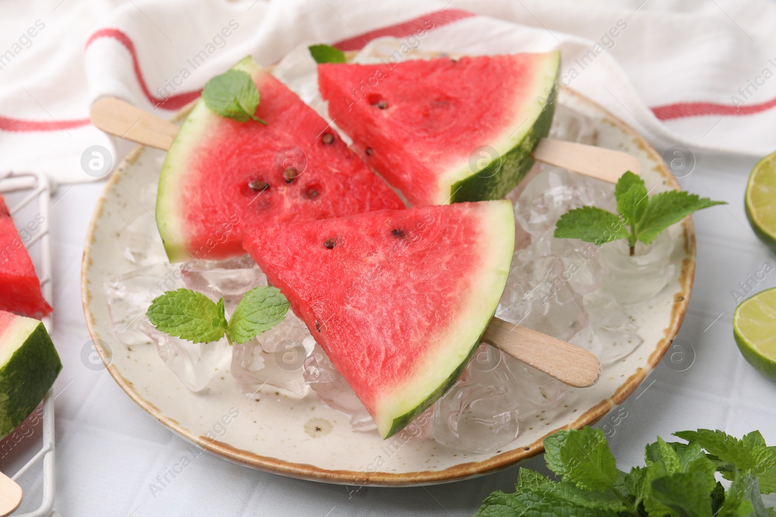 Photo of Pieces of tasty watermelon, ice cubes and mint on table, closeup