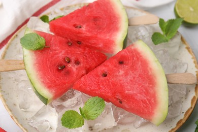 Photo of Pieces of tasty watermelon, ice cubes and mint on table, closeup