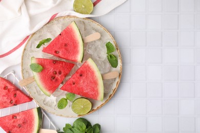 Photo of Pieces of tasty watermelon, ice cubes, lime and mint on white tiled table, flat lay. Space for text