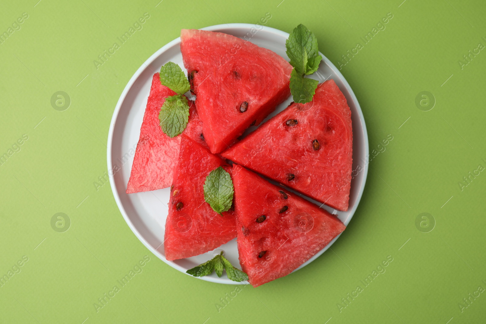 Photo of Pieces of tasty watermelon and mint on green table, top view