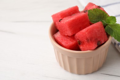 Photo of Pieces of tasty watermelon and mint in bowl on white table, closeup. Space for text