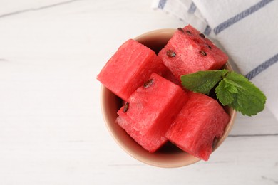 Photo of Pieces of tasty watermelon and mint in bowl on white table, top view. Space for text