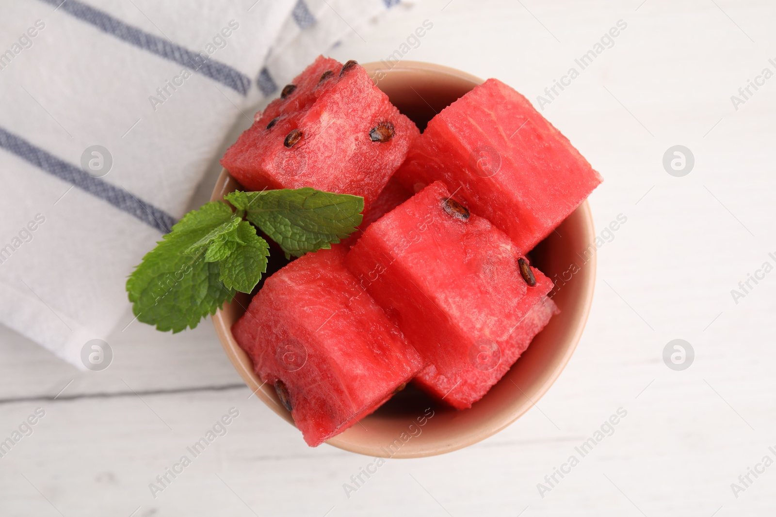 Photo of Pieces of tasty watermelon and mint in bowl on white table, top view