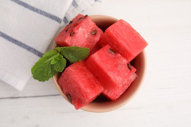 Photo of Pieces of tasty watermelon and mint in bowl on white table, top view