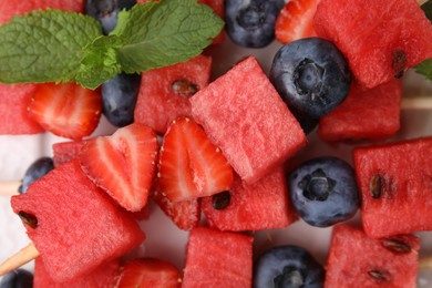 Photo of Pieces of tasty watermelon, strawberries, blueberries and mint on table, top view