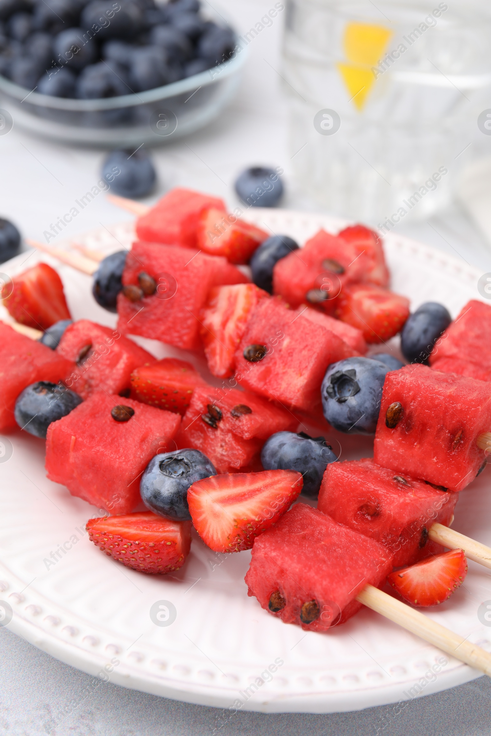 Photo of Skewers with tasty watermelon, strawberries and blueberries on table, closeup