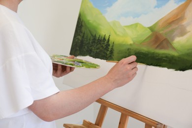 Photo of Woman drawing landscape with brush in studio, closeup