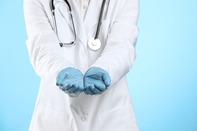 Doctor holding something on light blue background, closeup