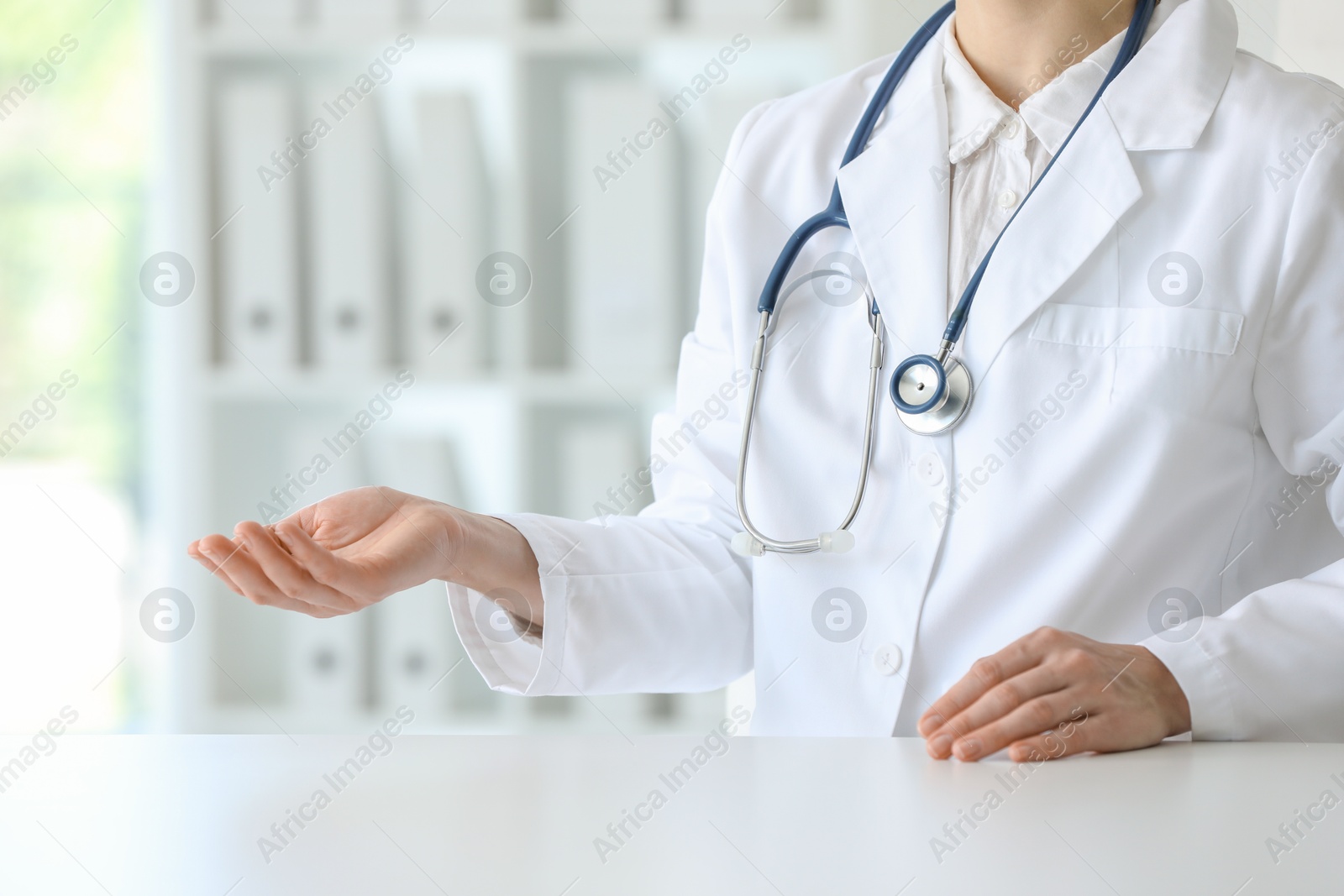 Photo of Doctor with stethoscope holding something at table in clinic, closeup