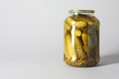 Pickled cucumbers in jar on light background. Space for text