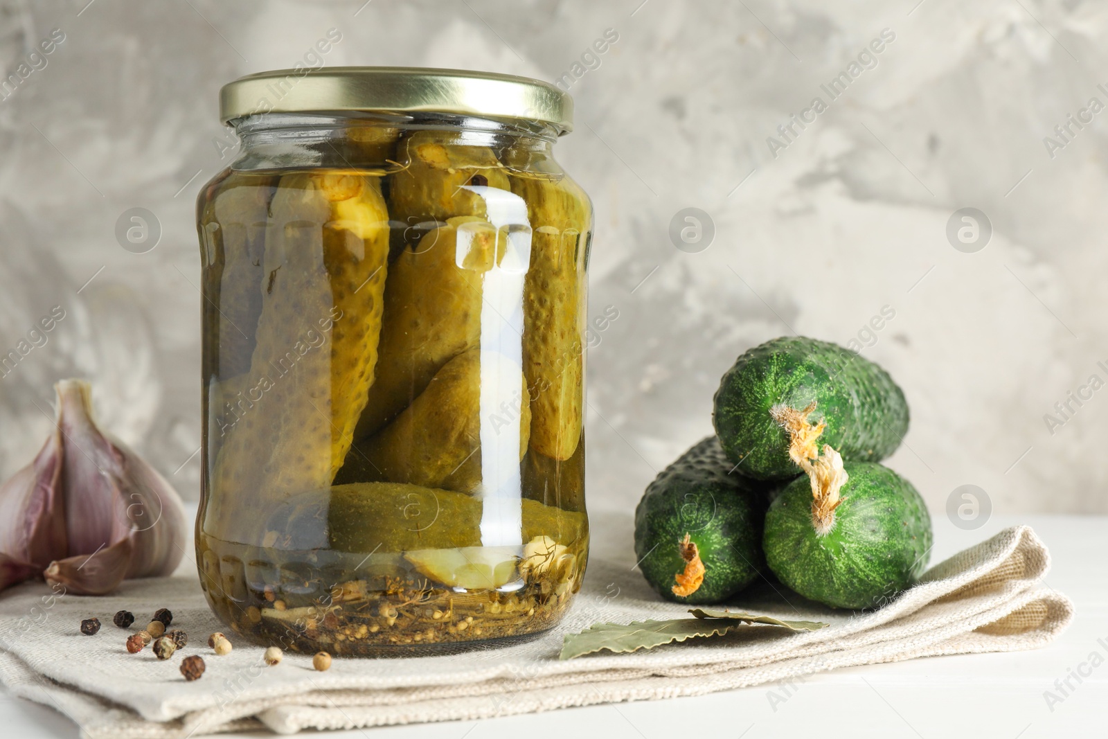 Photo of Pickles in jar, fresh cucumbers and spices on white table