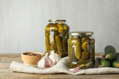 Photo of Pickles in jars, fresh cucumbers and spices on wooden table