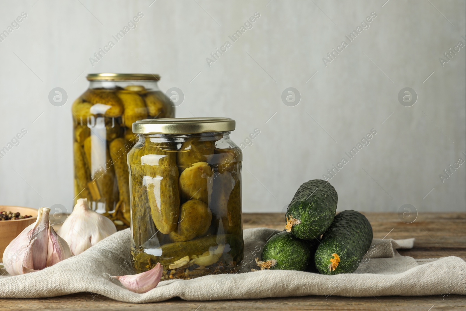 Photo of Pickles in jars, fresh cucumbers and spices on wooden table