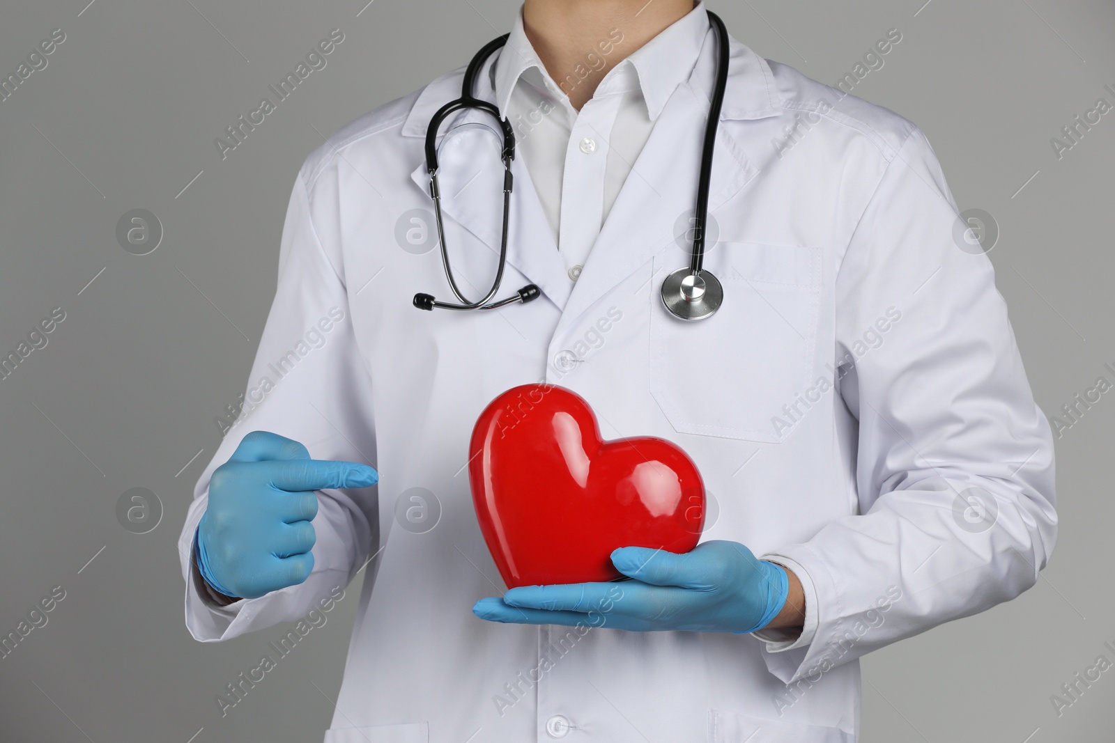 Photo of Doctor with red heart on grey background, closeup