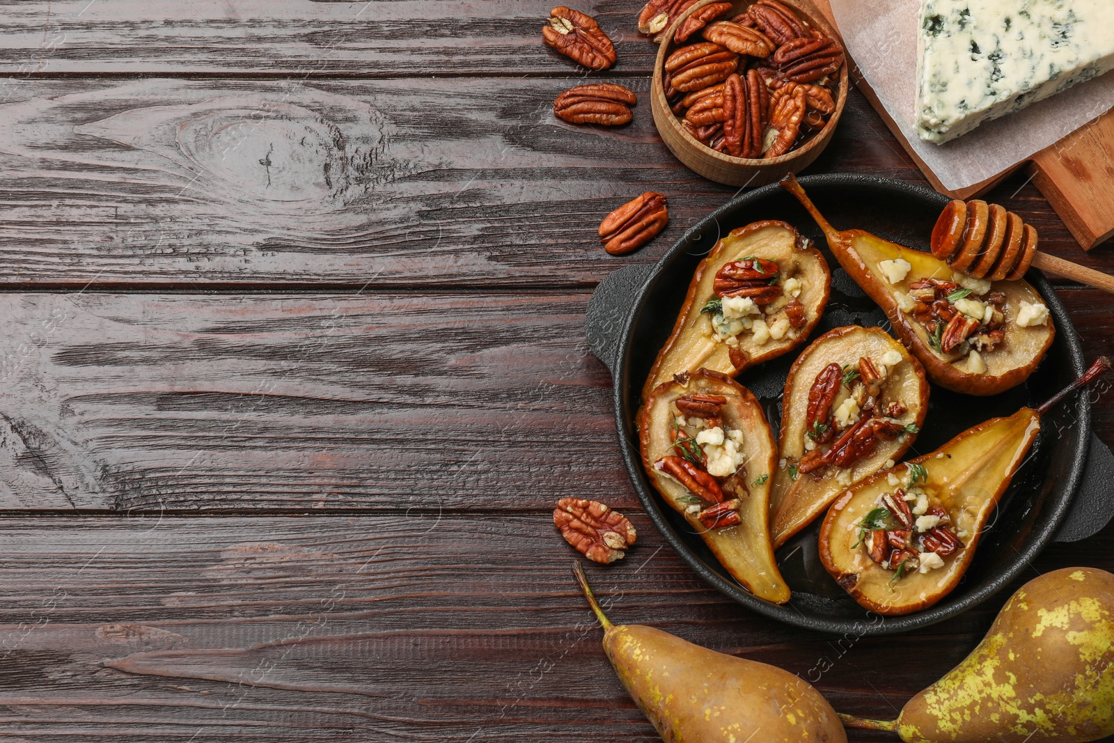 Photo of Delicious baked pears with nuts, blue cheese and honey on wooden table, flat lay. Space for text