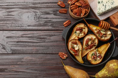 Delicious baked pears with nuts, blue cheese and honey on wooden table, flat lay. Space for text